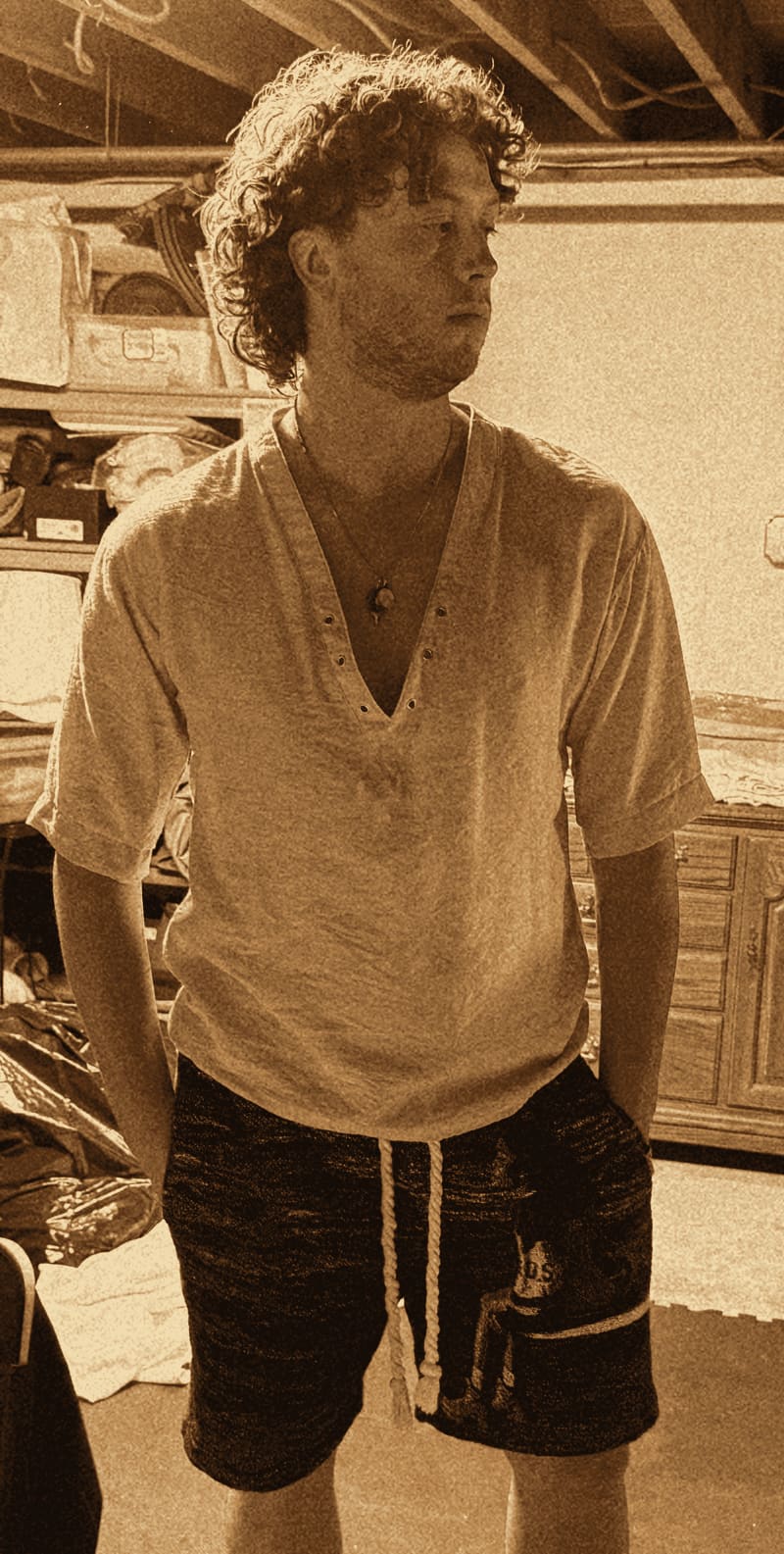 Exhibit D: the suspect in a deep-V linen shirt open to the sternum, a shark-tooth necklace resting in the gap and the drawstring tied in a bow, gazing past the camera like it owes him an apology.