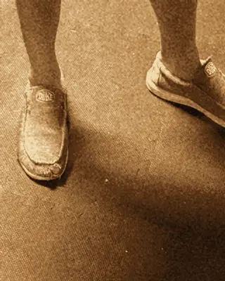 Close-up of grey slip-on shoes on a basement floor.