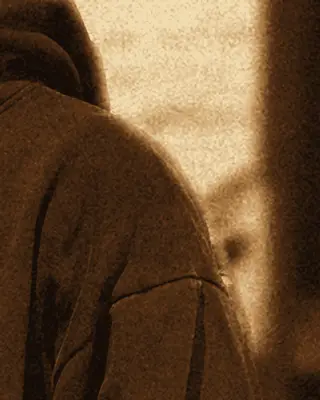 Close-up of a navy hoodie shoulder against white brick.